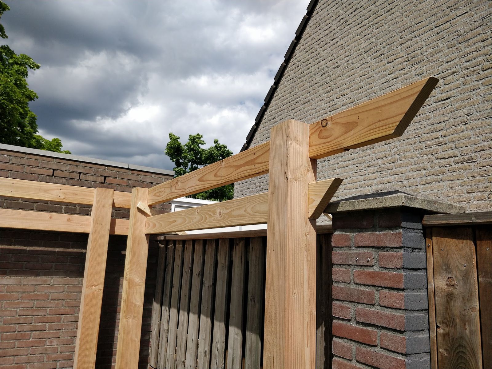 Douglas pergola in aanbouw tegen een bakstenen gevel