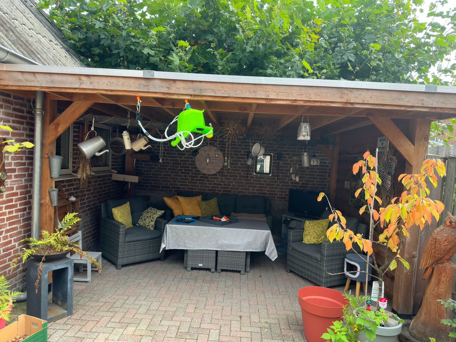 Houten afdak in de tuin met een loungeset en planten